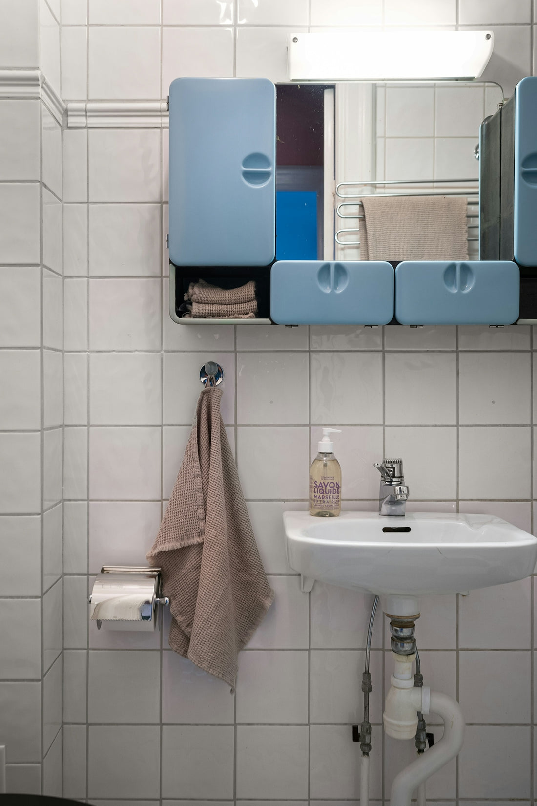 A bathroom with a sink, mirror and towel rack