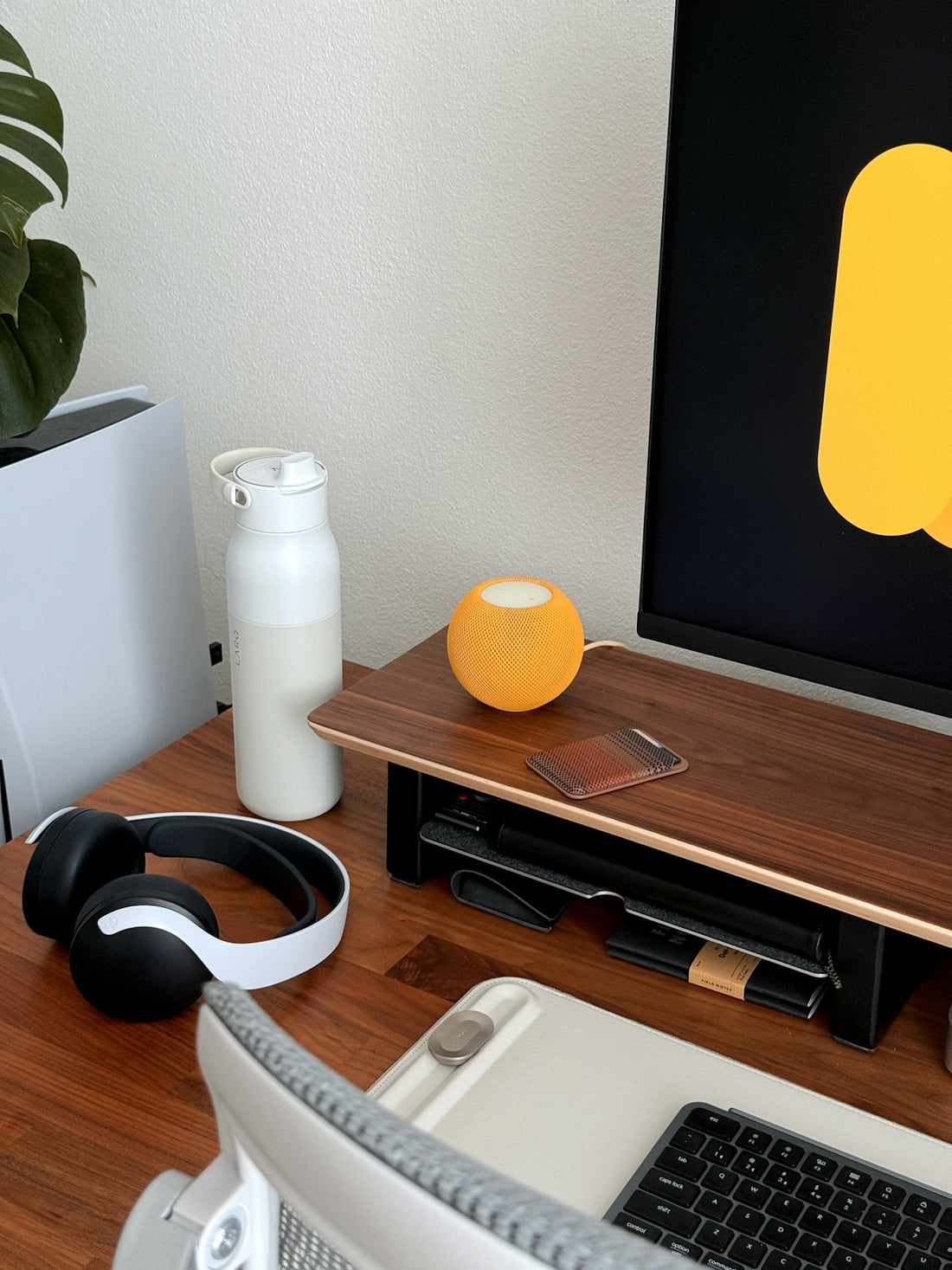 Desk setup with monitor, headphones, and water bottle.