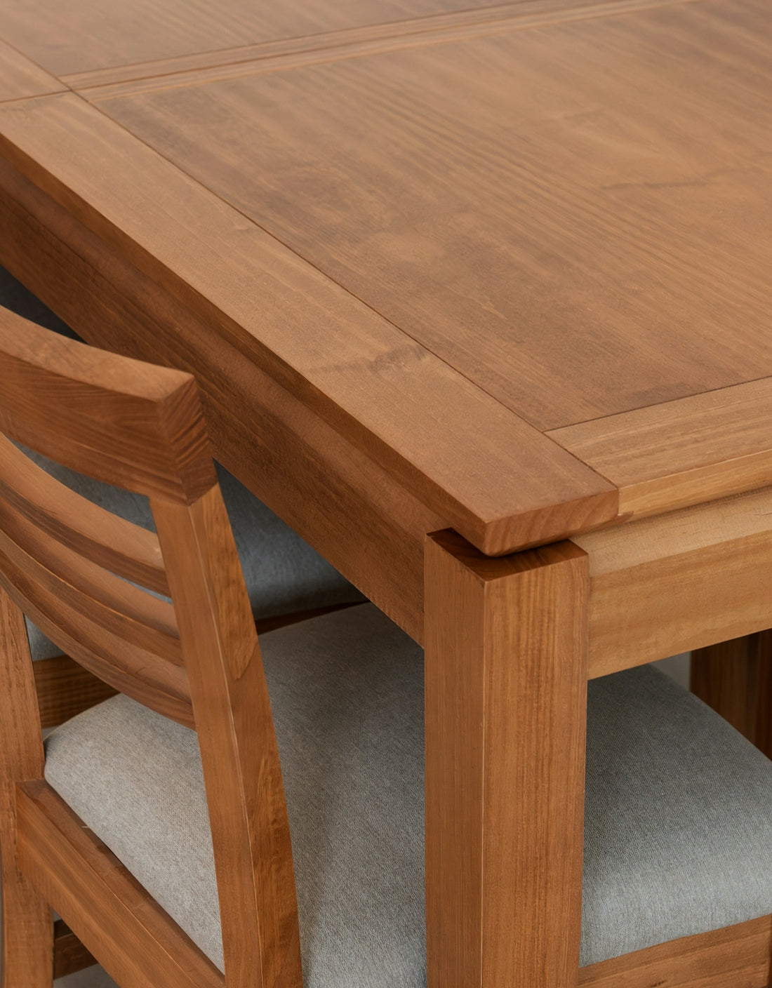 Wooden dining table and chairs with grey upholstery.