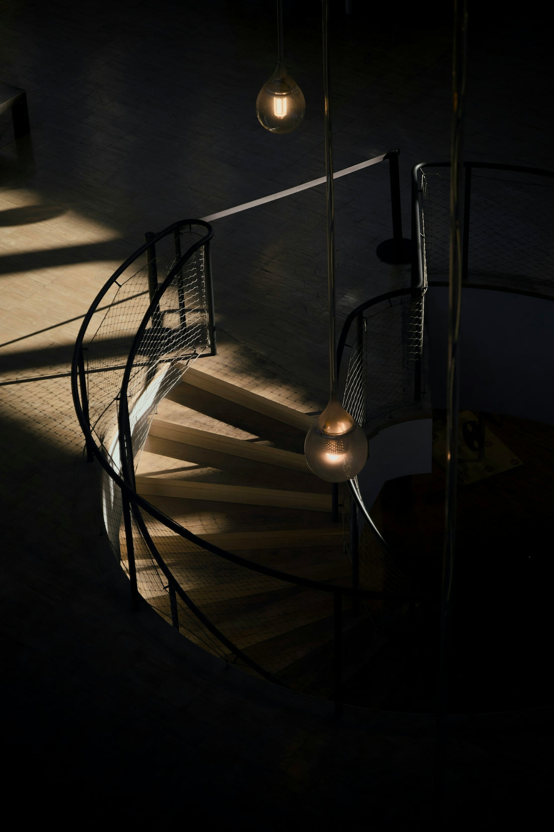A modern spiral staircase with warm ambient lighting.