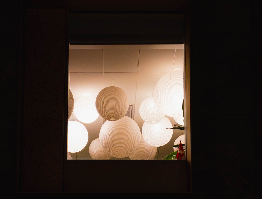 Several white paper lanterns illuminated indoors at night.
