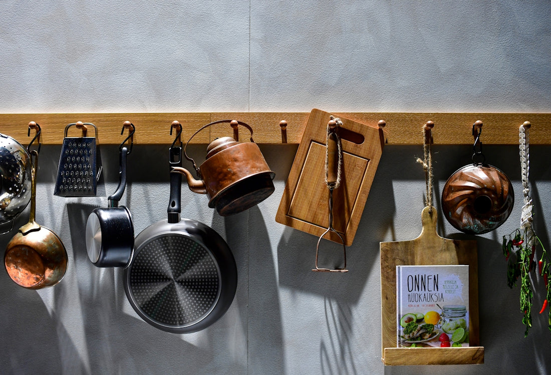 Kitchenware hanging on a wooden rack against wall.