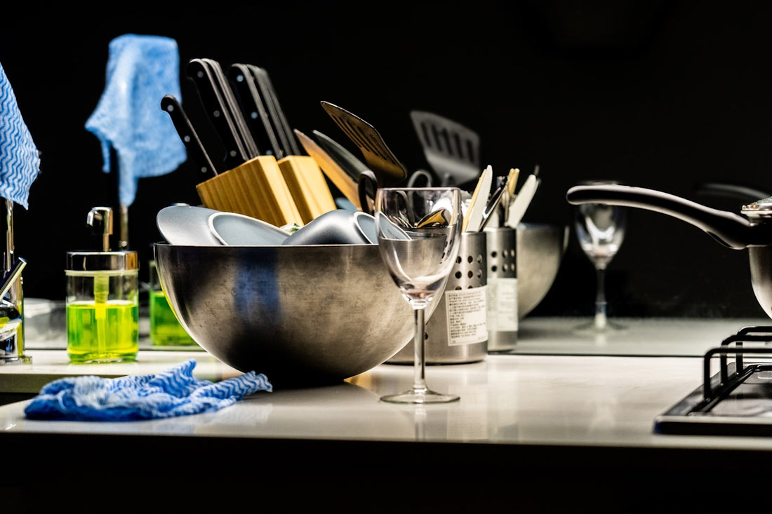 A kitchen sink with dishes and cleaning supplies.