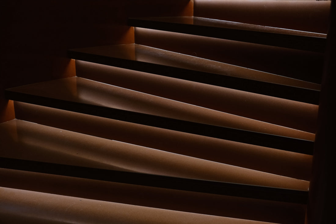 Wooden stairs with dramatic lighting and shadows.