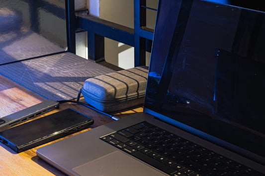 Laptop, phone, and charger on a wooden desk.