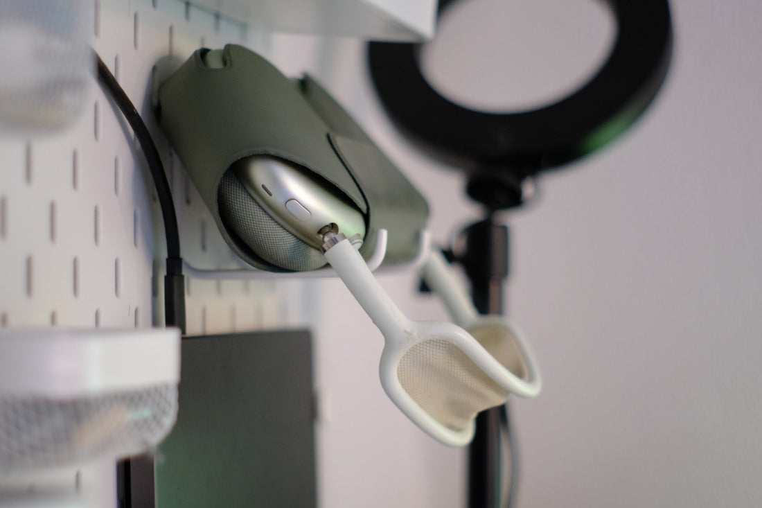Green apple airpods max headphones hanging on a white pegboard.