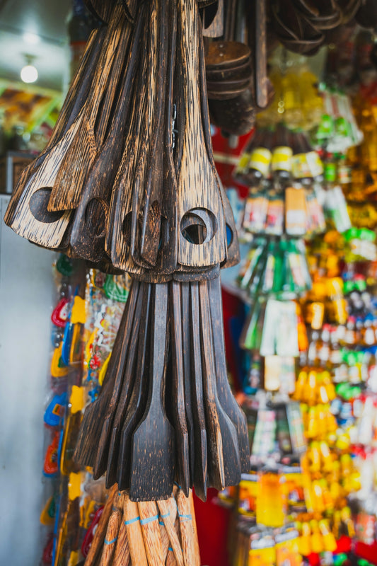 Dark wooden kitchen tools hanging in a vibrant market.