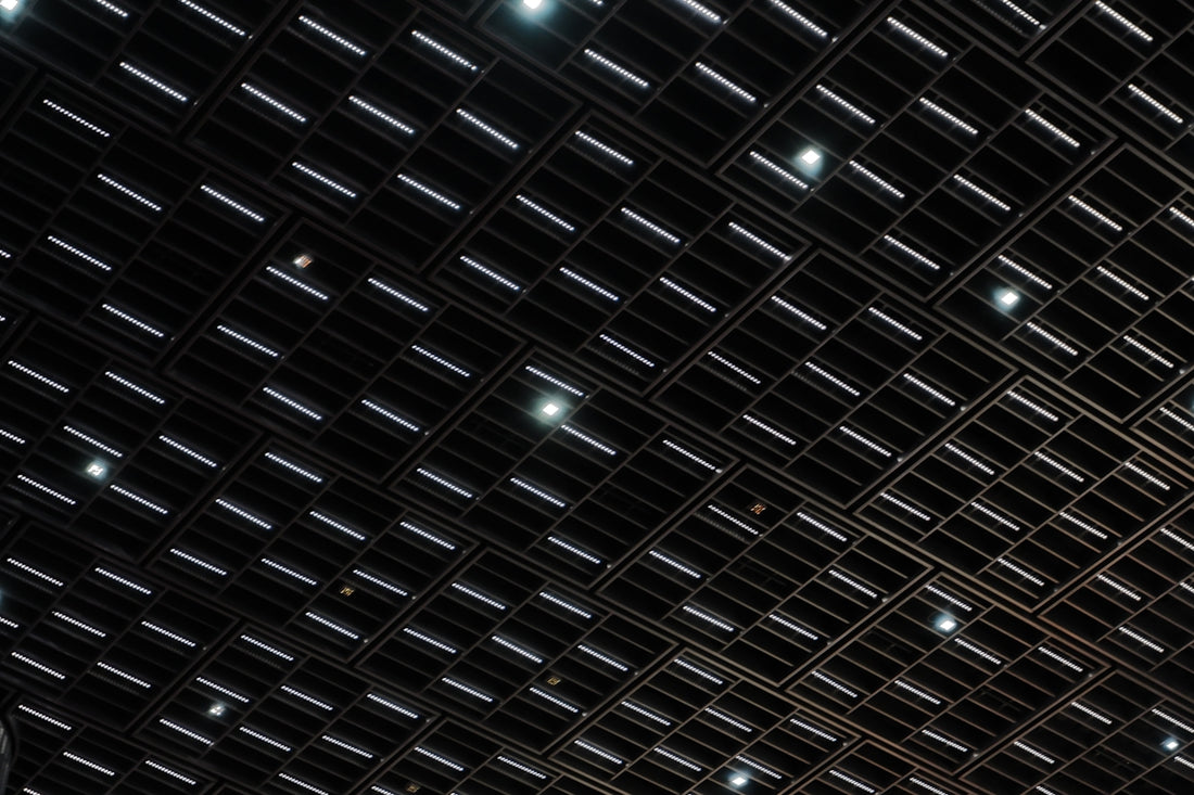 Dark ceiling with grid of rectangular and circular lights.