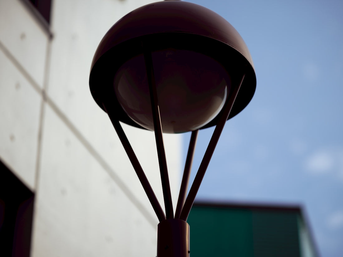 A modern street lamp against a blue sky and building.